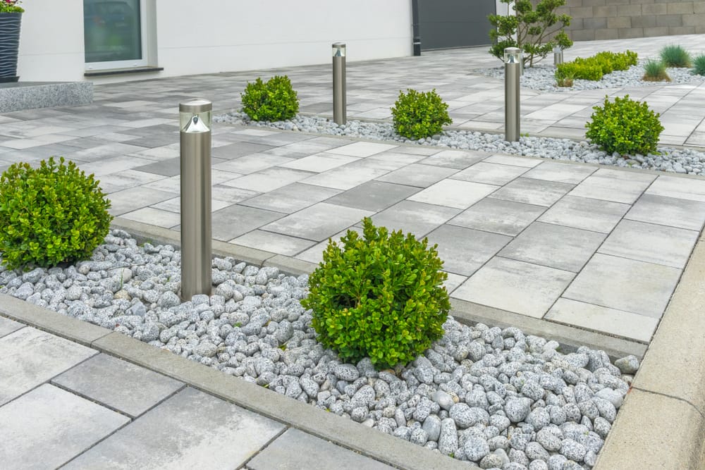front garden with grey paving, pebbles and miniature bushes