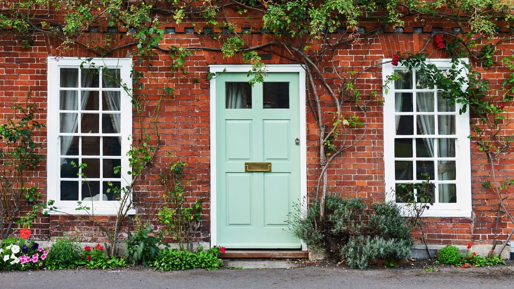 exterior of a house on a london street, including green door and climbing plants on brick
